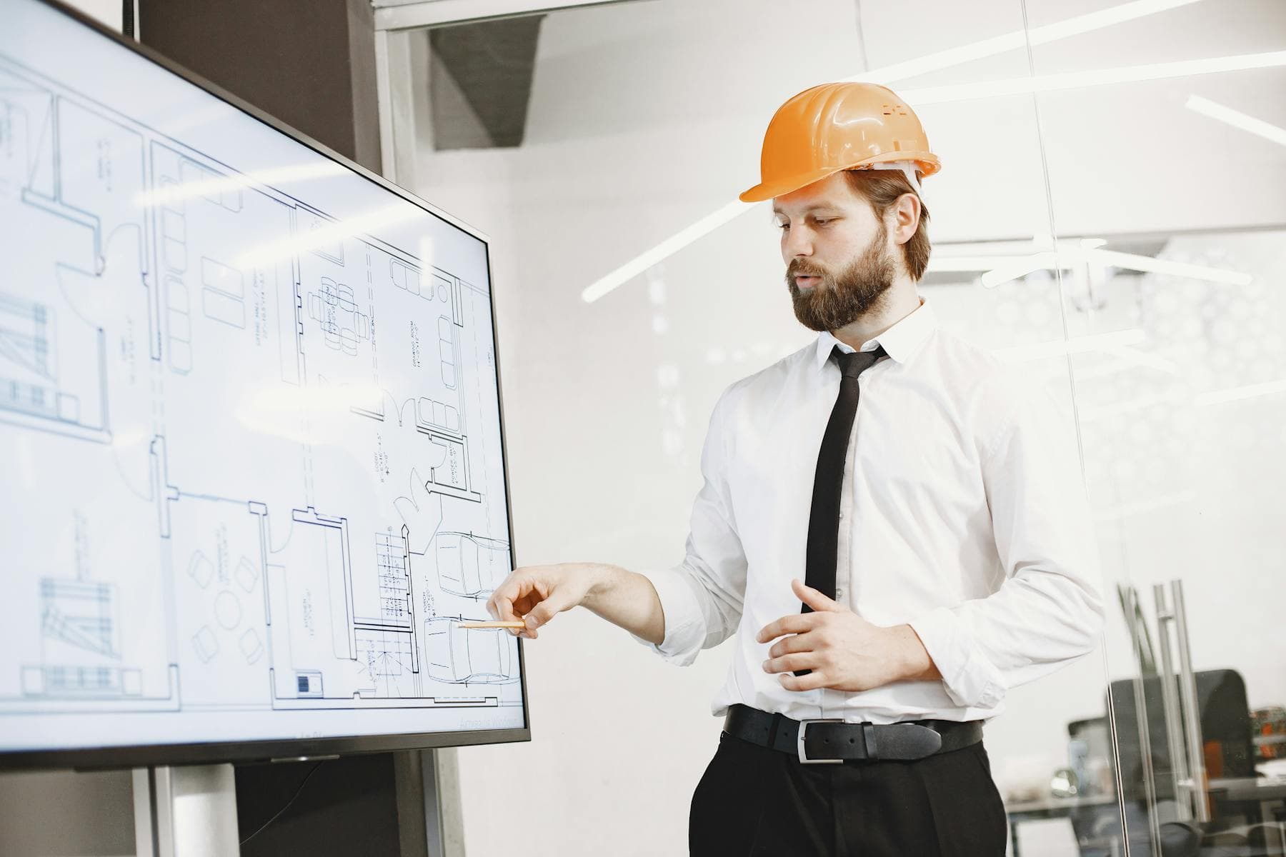 Architect reviewing plans on a screen with hard-hat stakeholders