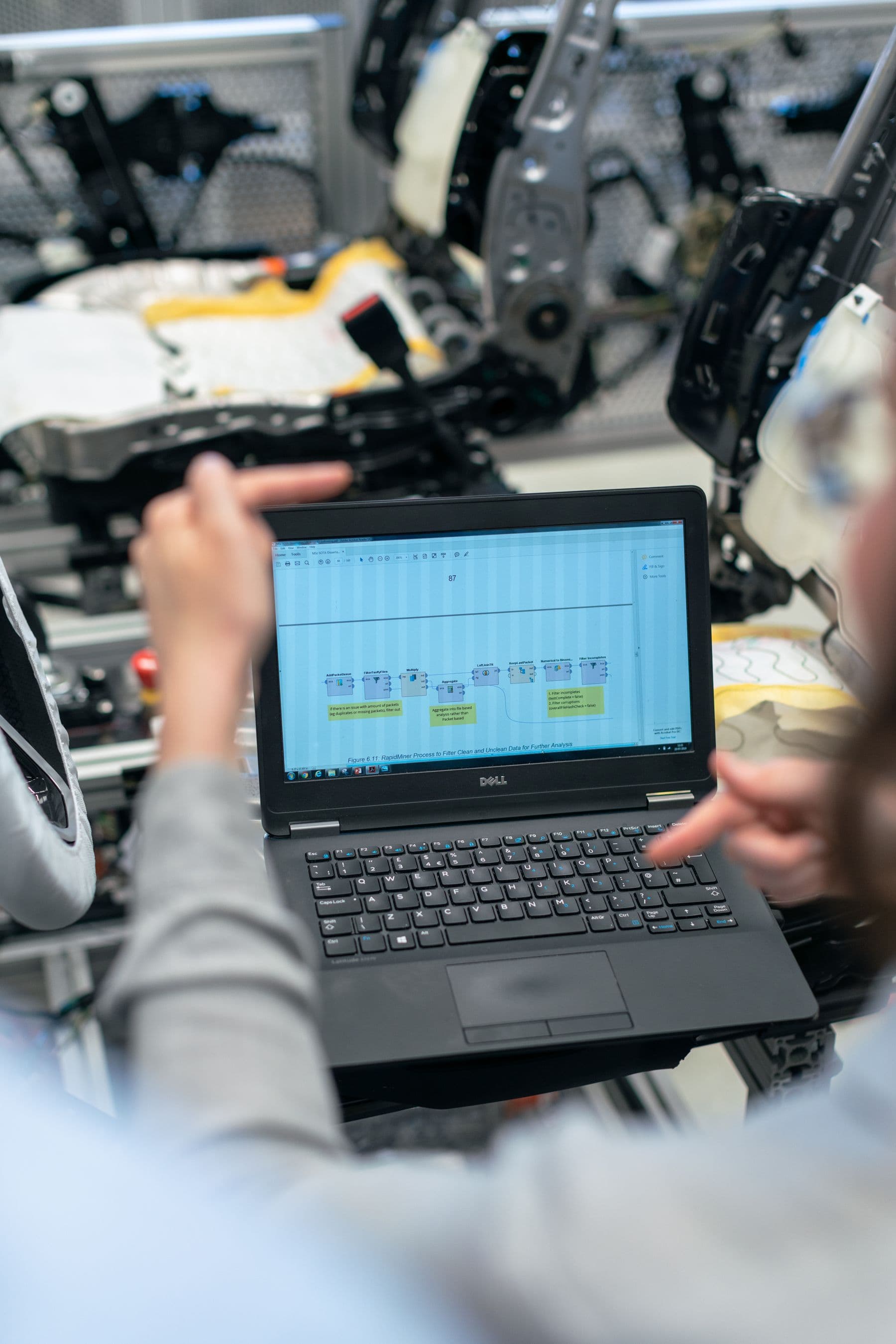 Engineers using a laptop to analyze software data in an industrial workshop