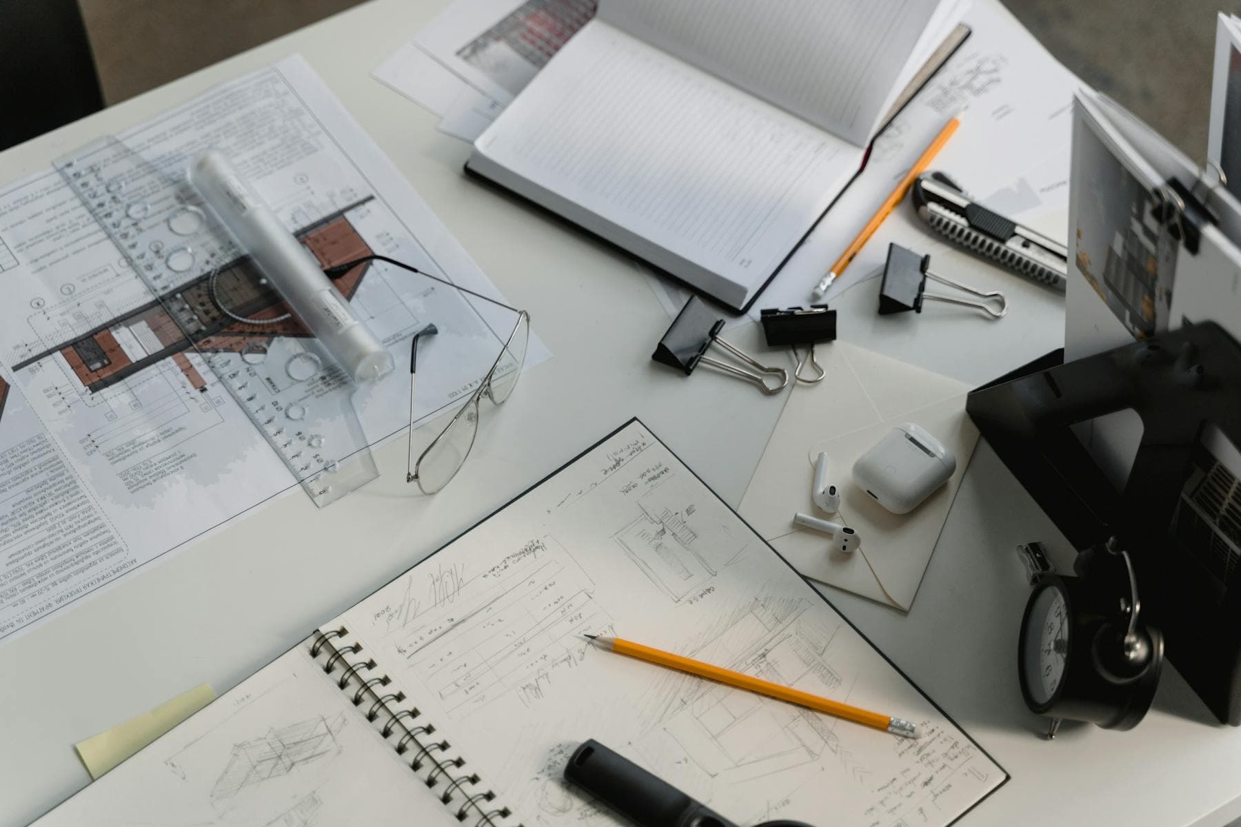 Busy architectural workspace with blueprints, sketches, and drafting tools