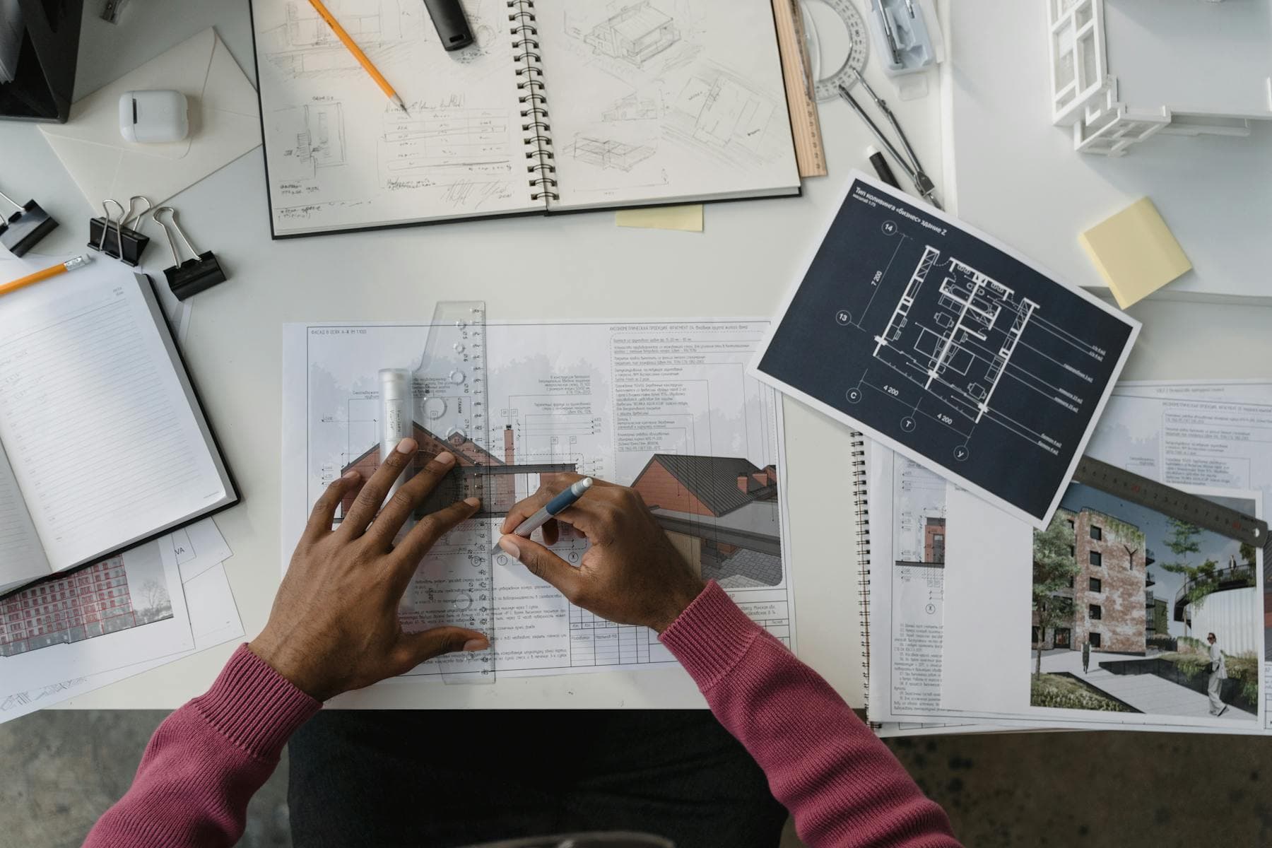 Architect designing plans at a desk surrounded by tools and blueprints